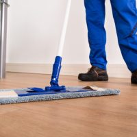 man with flat broom cleaning floors